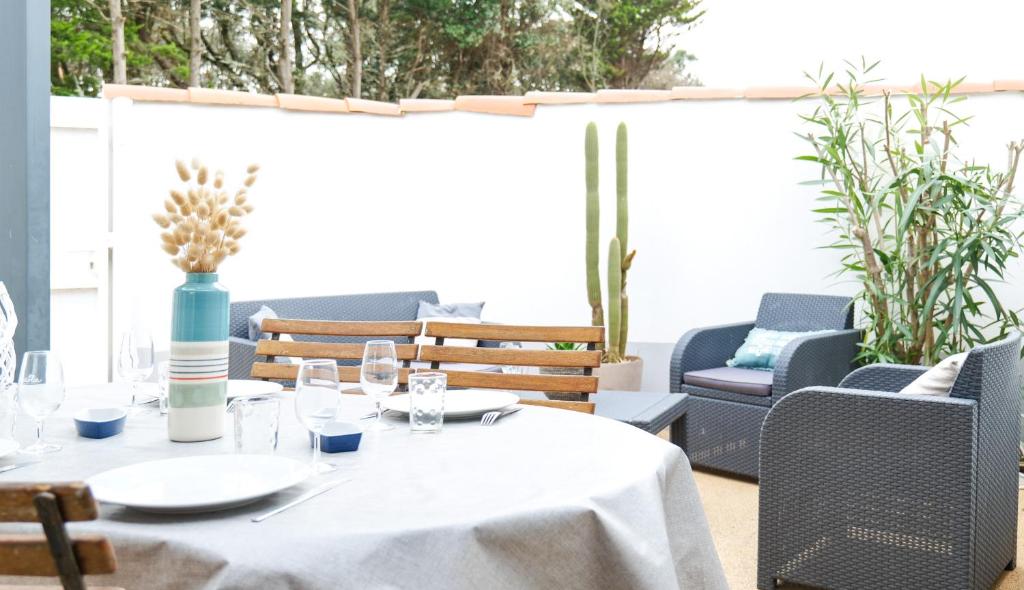 une table avec un tissu de table blanc sur une terrasse dans l'établissement Maison dans résidence proche océan Les Sables - 4 pers, à Saint-Hilaire-de-Talmont