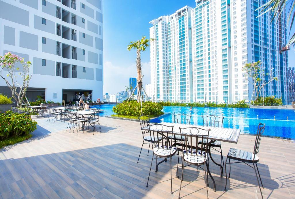 a patio with tables and chairs in front of buildings at Stay With Me Saigon Apartment - Rivergate Residence in Ho Chi Minh City