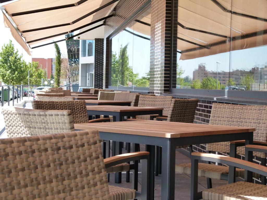 a restaurant with tables and chairs and windows at Hotel Río Hortega in Valladolid