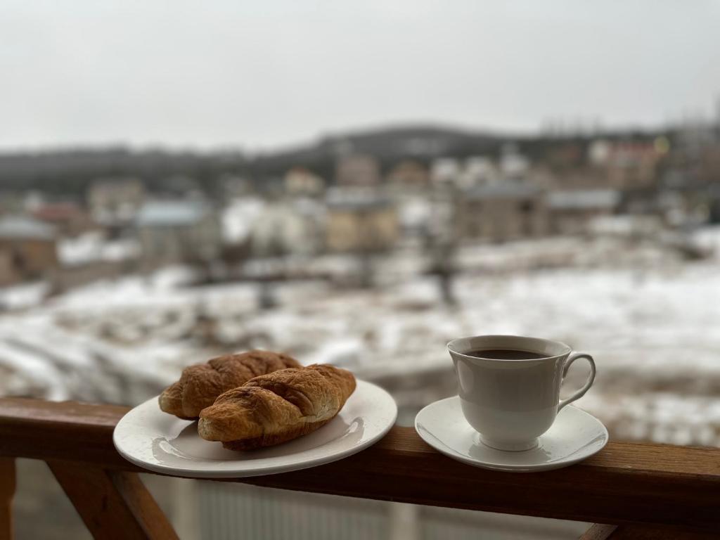 two croissants and a cup of coffee on a balcony at Коттедж в Цахкадзоре in Tsaghkadzor