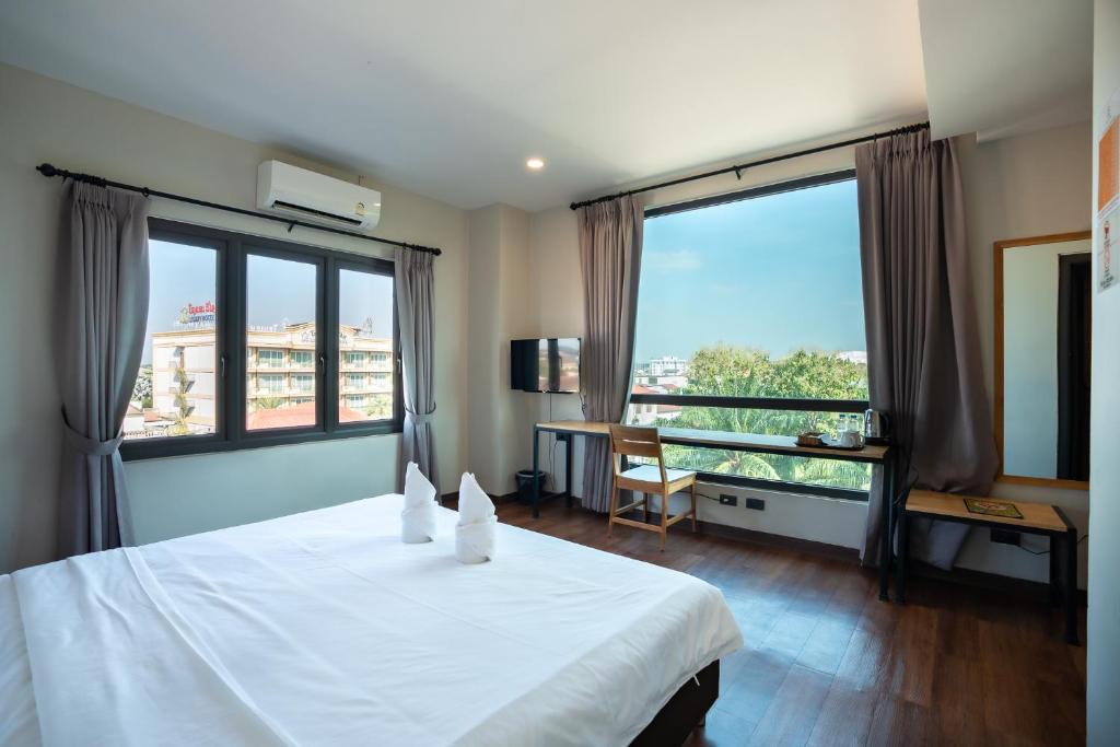 a bedroom with a white bed and large windows at Siri Hotel in Vientiane