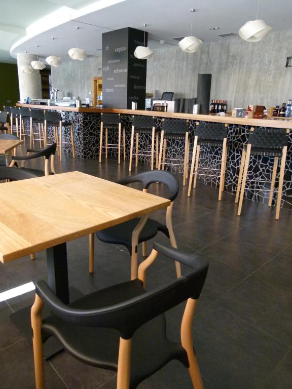 a cafeteria with a wooden table and chairs and a bar at Hotel Río Hortega in Valladolid