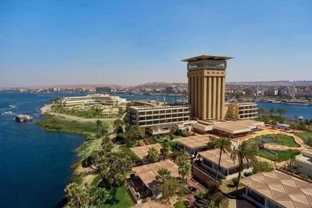 a building with a clock tower next to the water at Salah El Din Restaurant on the Nile Corniche in Aswan