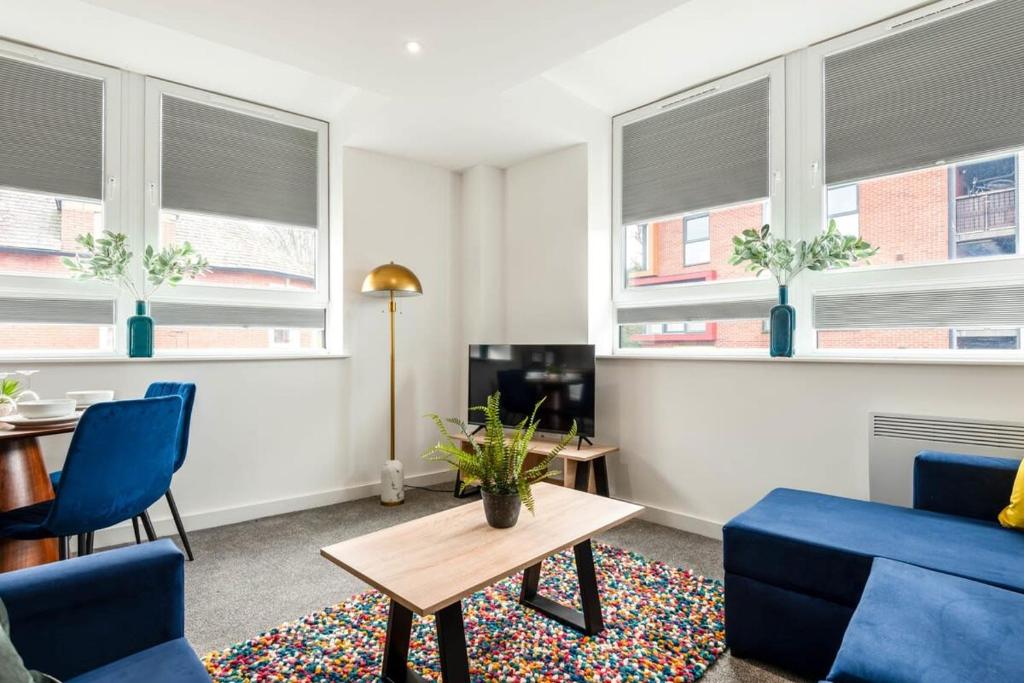 a living room with blue chairs and a table and windows at Bright 1 Bedroom Apartment in Central Rotherham in Rotherham