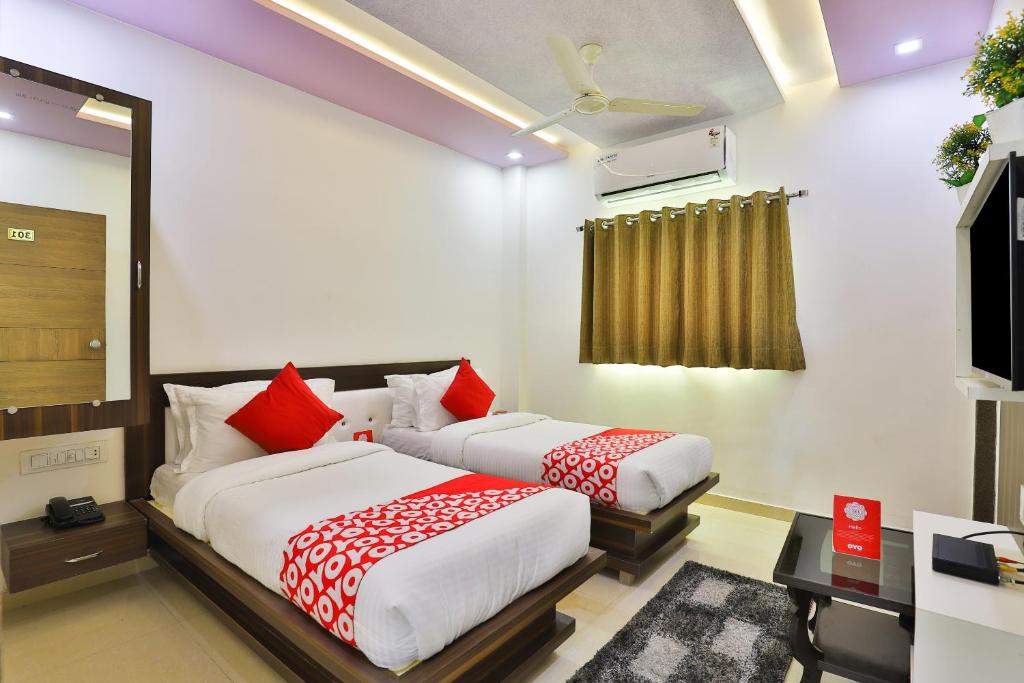 two beds in a room with red and white pillows at Flagship Hotel Navjivan in Bātwa