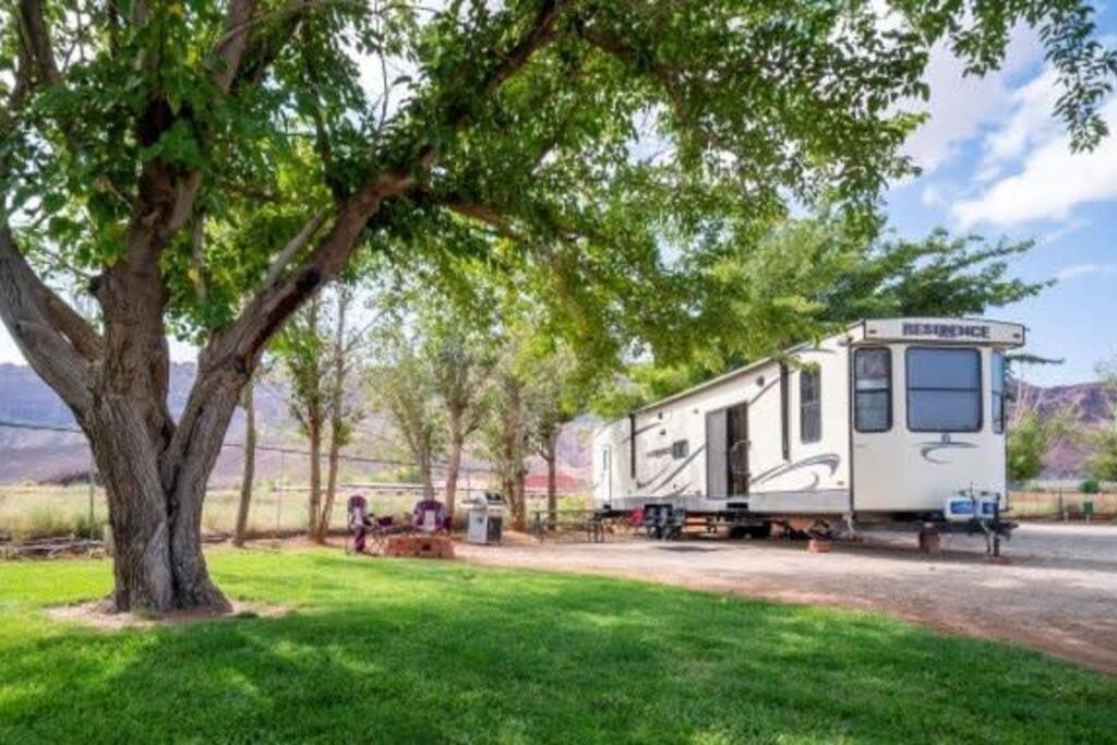 a trailer parked under a tree in a field at Moab RV Resort Outdoor Glamping Destination RV OK40 in Moab