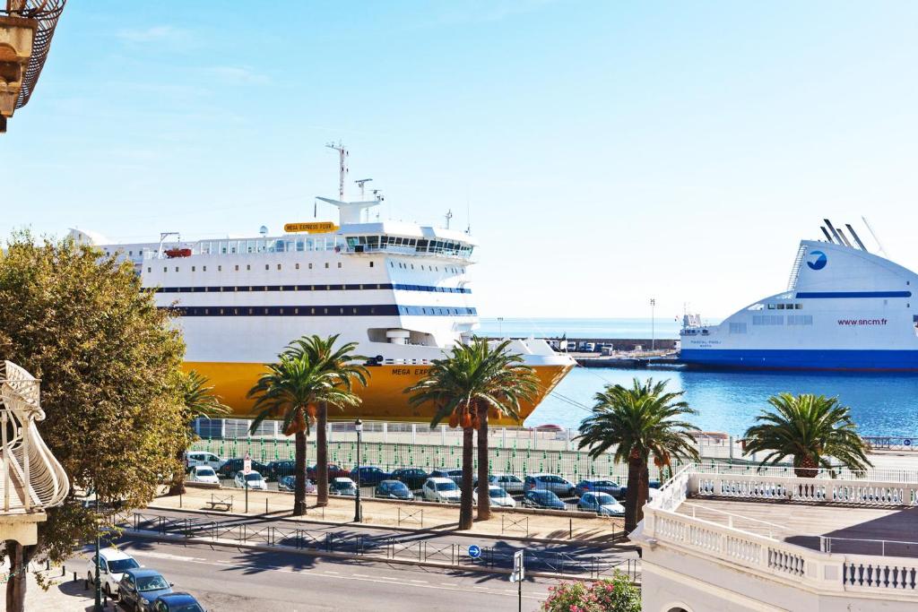 um navio de cruzeiro atracado num porto com palmeiras em Hotel Riviera em Bastia