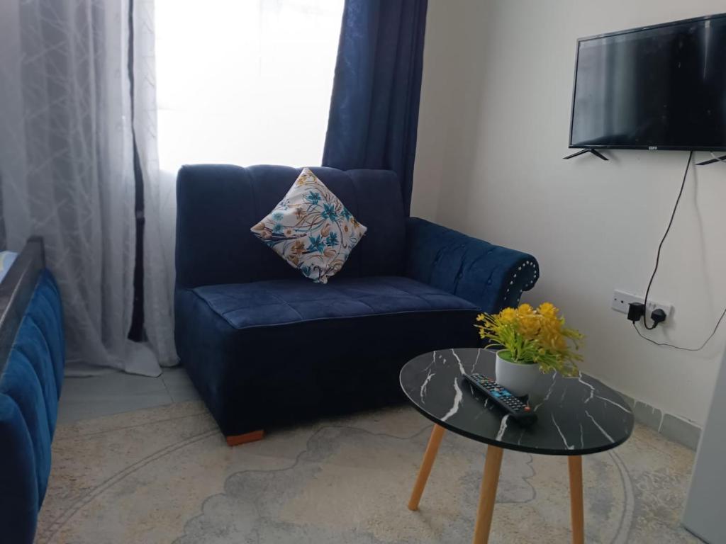 ein Wohnzimmer mit einem blauen Sofa und einem Tisch in der Unterkunft Ruby in Nairobi