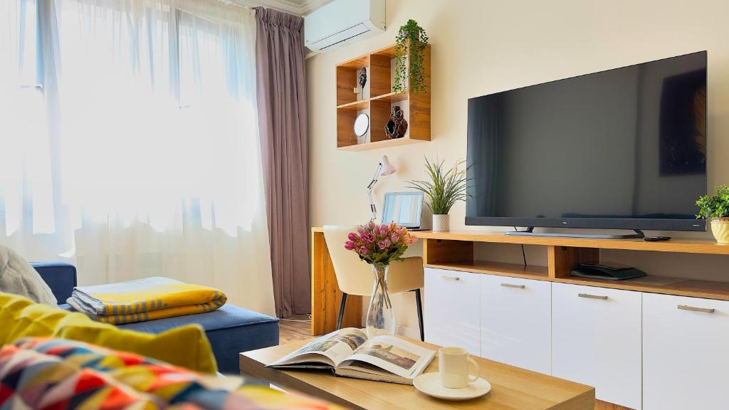 una sala de estar con TV y un jarrón de flores en Уютная 2-комнатная квартира в центре г. Алматы, en Almaty