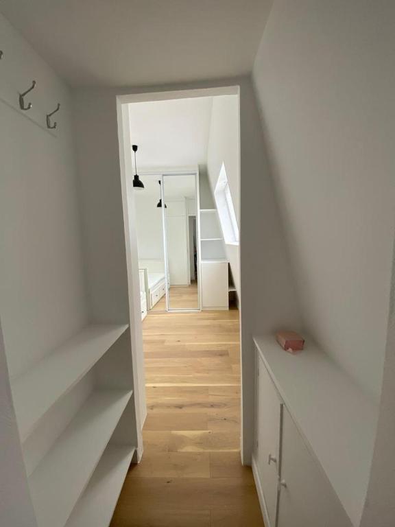 Cette chambre est dotée de murs blancs et d'un escalier avec des étagères blanches. dans l'établissement Église de pontoise, à Pontoise