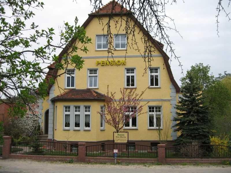 un edificio amarillo con un cartel delante en Pension Villa Martha, en Burg Stargard