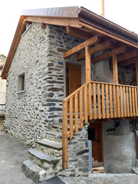 een stenen huis met een houten terras erop bij Majagatt Holiday Home in Roveredo