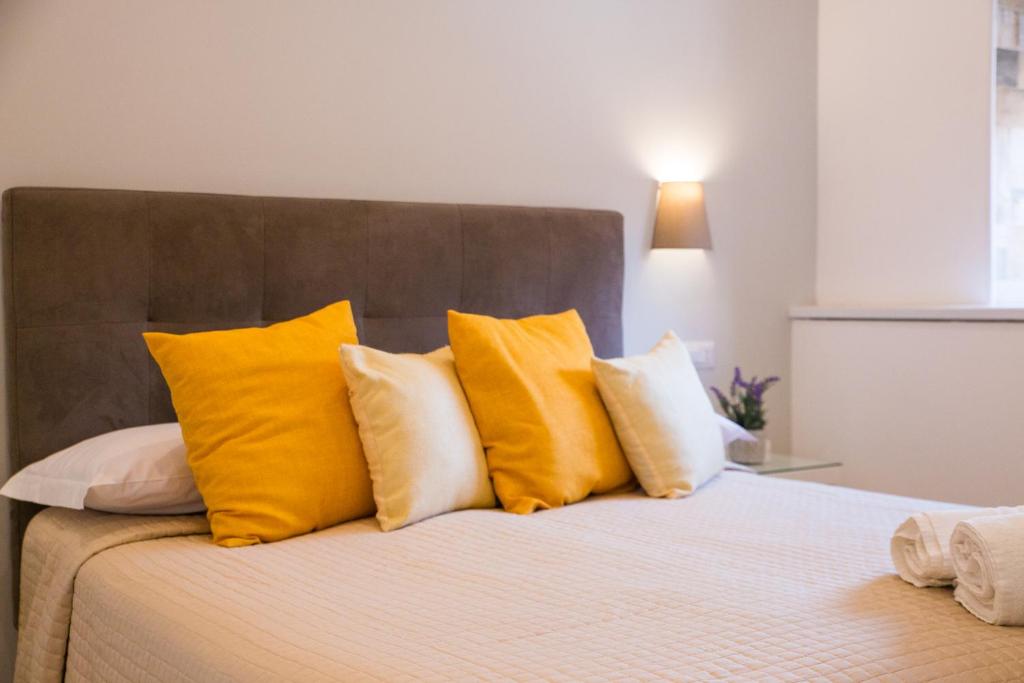 Hotel Rivoli Sorrento في سورينتو: سرير عليه وسائد صفراء وبيضاء