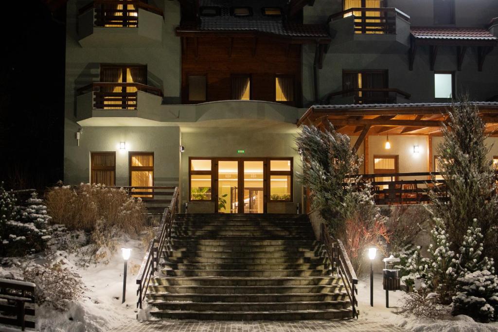 a house with stairs in the snow at night at Pensiunea Heveder in Praid