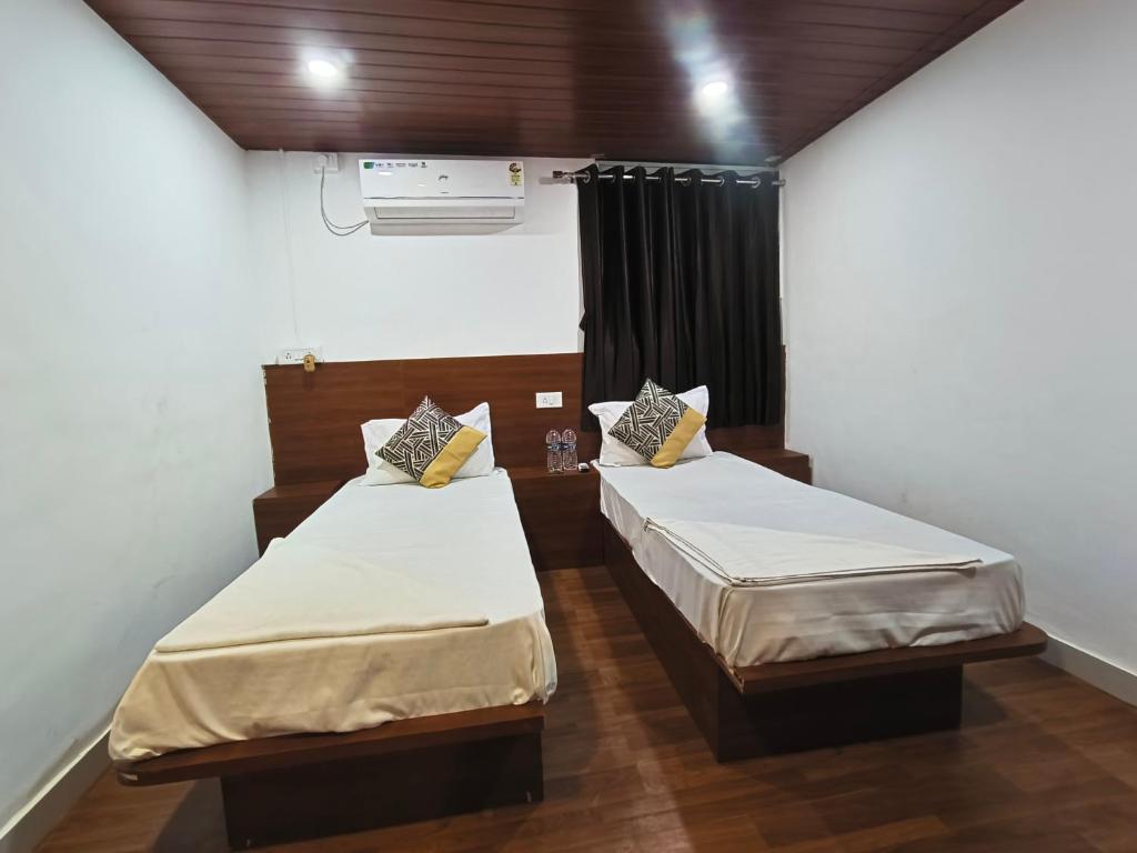 a room with two beds in a room with a fan at Paradise inn in Alandi