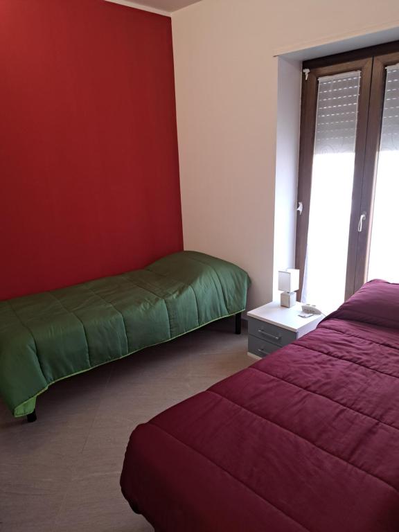 1 Schlafzimmer mit 2 Betten und einer roten Wand in der Unterkunft Cappuccini Guest House in San Giovanni in Fiore