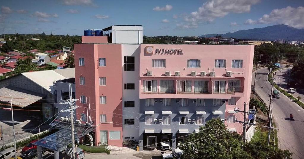 バタンガスにあるJVJ HOTELS CORPORATIONの側面に看板が出たピンクの建物