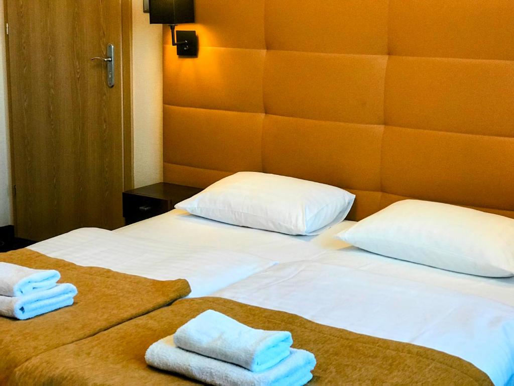 a hotel room with two beds with towels on them at La Petite APARTMENTS&ROOMS in Gdańsk