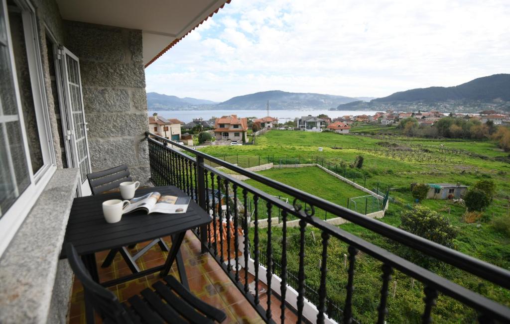 a balcony with a table with a view of a field at Casa Juncal sin cocina in Vilaboa