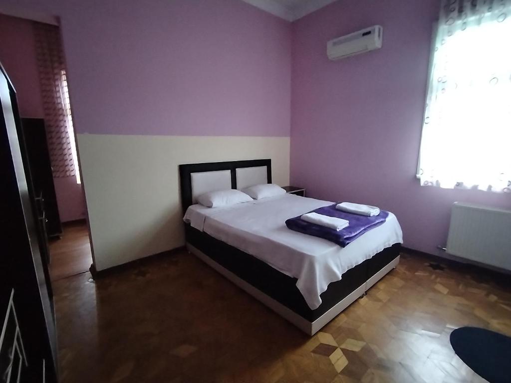 ein Schlafzimmer mit einem Bett in einem Zimmer mit lila Wänden in der Unterkunft BK GOLD HOTEL in Batumi