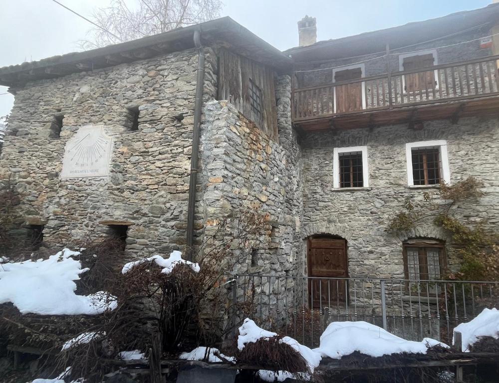un antiguo edificio de piedra con nieve en el suelo en L'Atelier du Temps - Casa Ronc, en Etroubles