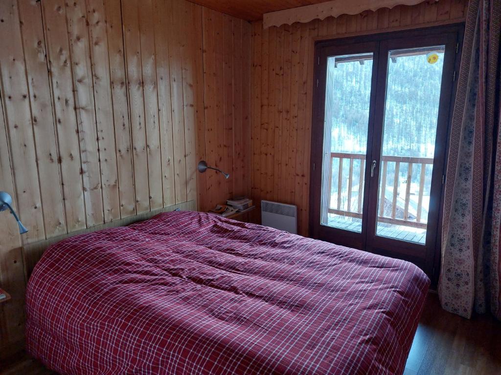 a bedroom with a bed with a red blanket and a window at Les Airelles 33, Le coin, Molines en Queyras Classé 3 étoiles in Molines-en-Queyras
