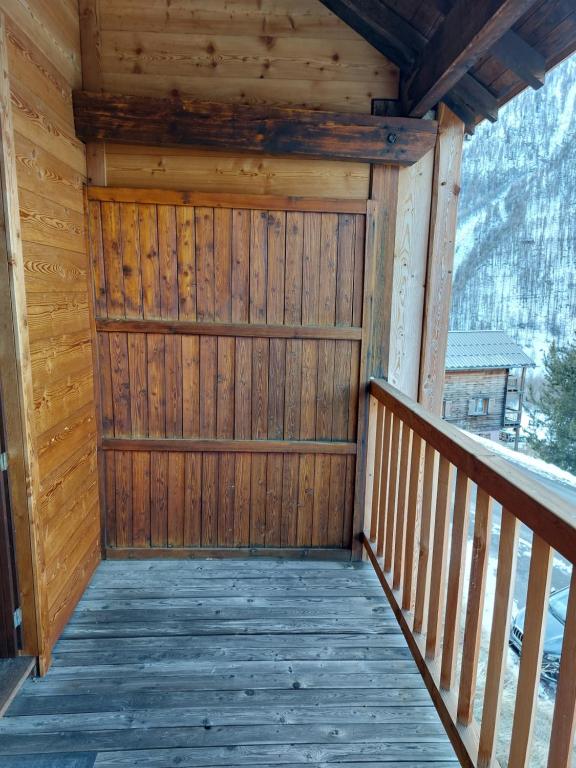 a wooden porch of a cabin with a wooden door at Les Airelles 33, Le coin, Molines en Queyras Classé 3 étoiles in Molines-en-Queyras