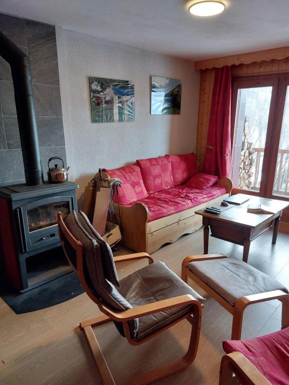 a living room with a red couch and a fireplace at Les Airelles 33, Le coin, Molines en Queyras Classé 3 étoiles in Molines-en-Queyras