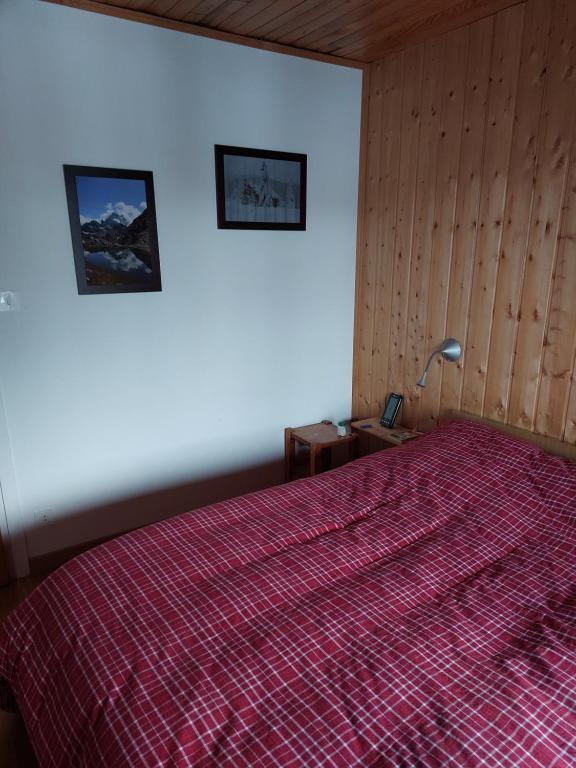a bedroom with a bed with a red comforter at Les Airelles 33, Le coin, Molines en Queyras Classé 3 étoiles in Molines-en-Queyras