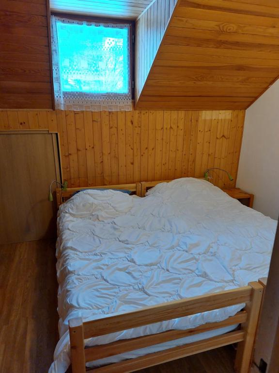 a bed in a wooden room with a window at Les Airelles 33, Le coin, Molines en Queyras Classé 3 étoiles in Molines-en-Queyras