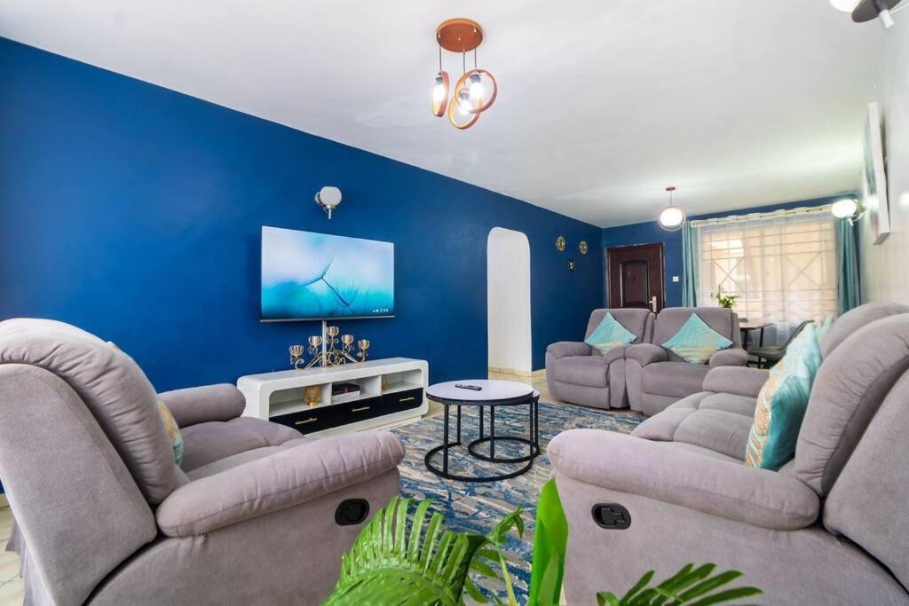 a living room with couches and a blue wall at Azure Skyline Villa, 3BR Modern Condo Nakuru City. in Nakuru