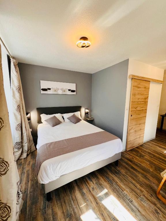 une chambre avec un grand lit blanc et du parquet dans l'établissement Logis Hôtel Le Relais Des Remparts, à Allanche
