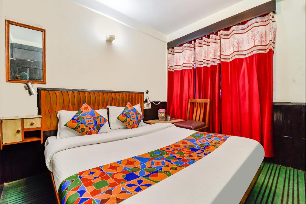 a bedroom with a bed and a red curtain at FabHotel Park View I in Manāli