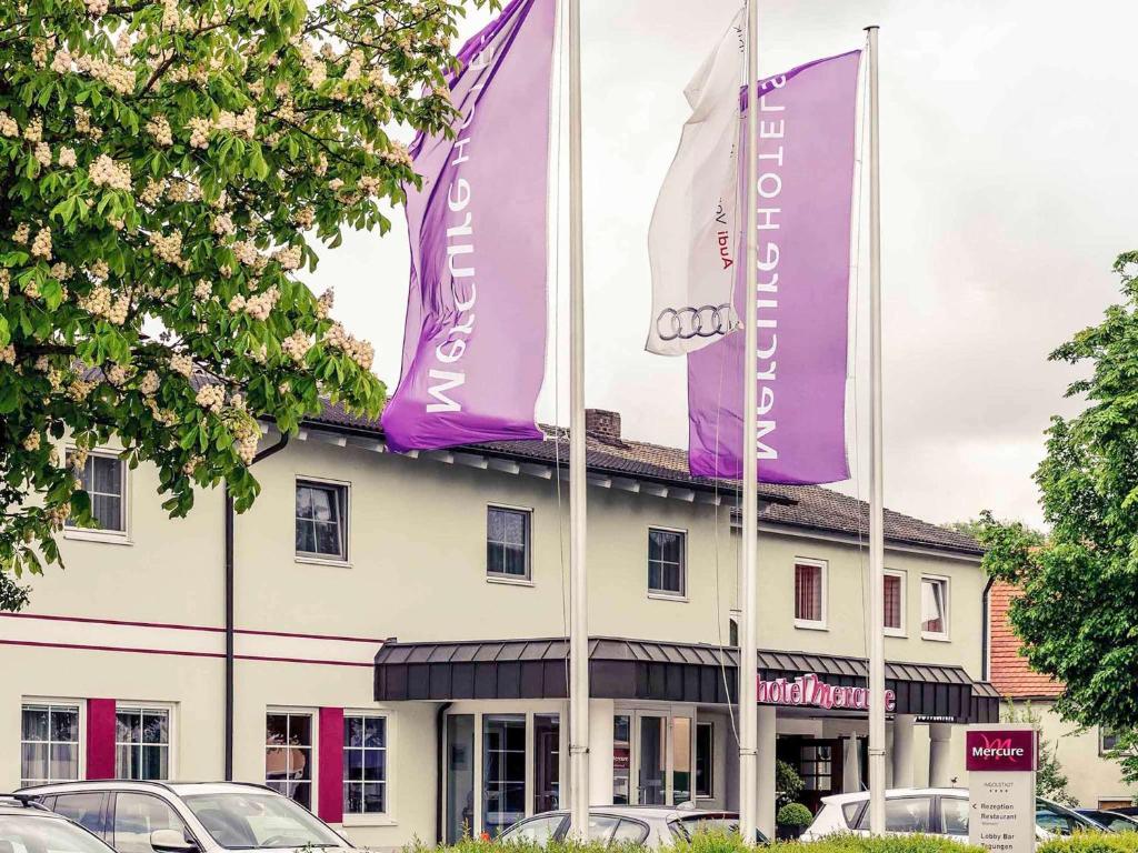a building with purple and white flags in front of it at Mercure Hotel Ingolstadt in Ingolstadt