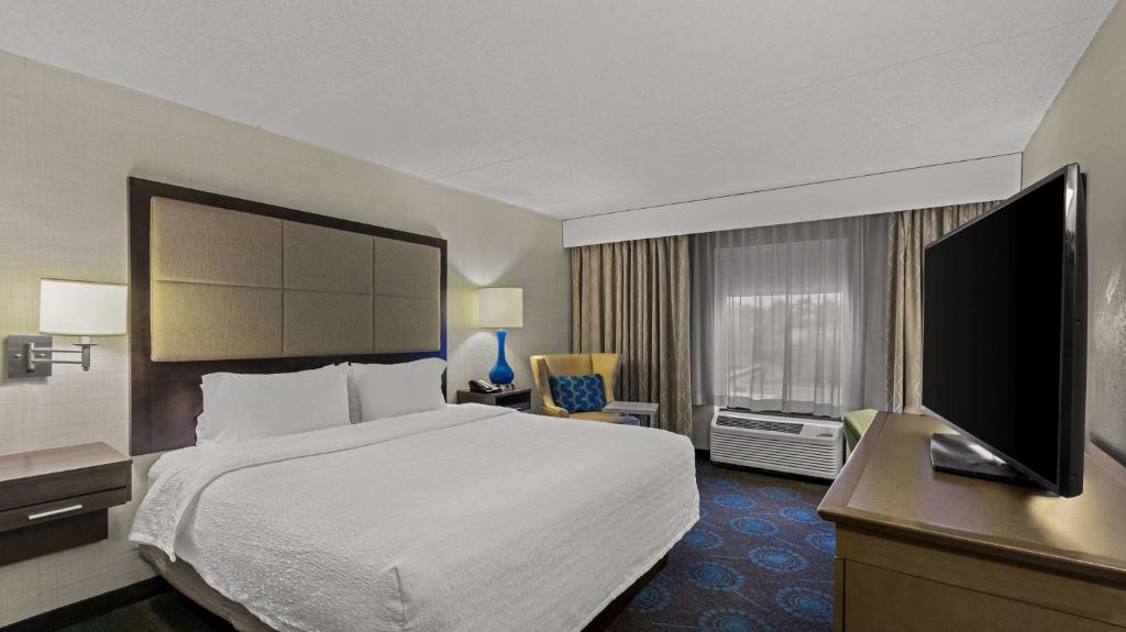 um quarto de hotel com uma cama e uma televisão de ecrã plano em Hampton Inn Bloomington em Bloomington