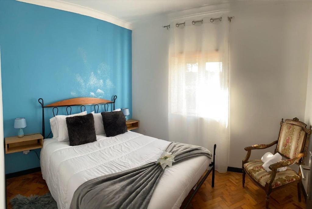 1 dormitorio con paredes azules, 1 cama y 1 silla en Alojamento D Duarte T1, en Gouveia