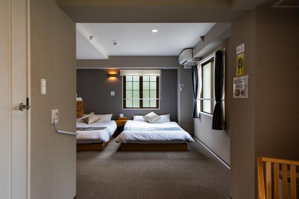 Hotel Neiraku في نارا: غرفة نوم بسريرين ونافذة