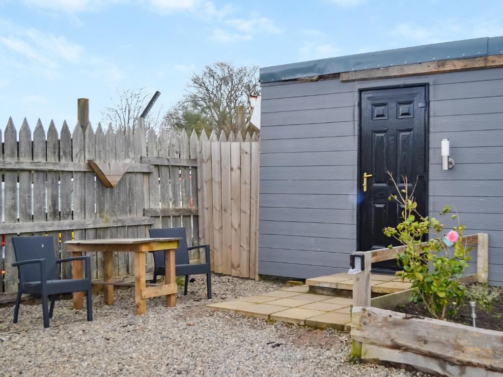 a small blue shed with a table and a wooden fence at Wee Shot - Uk46613 in Tain