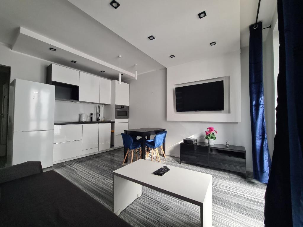 a living room with a table and a white kitchen at Apartament z kuchnią dla 4 osób w centrum Bydgoszczy in Bydgoszcz