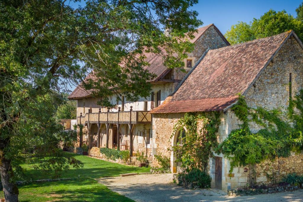 - une vue sur l'extérieur d'une grande maison en pierre avec des arbres dans l'établissement Domaine Médiéval à Bergerac, à Montagnac-la-Crempse