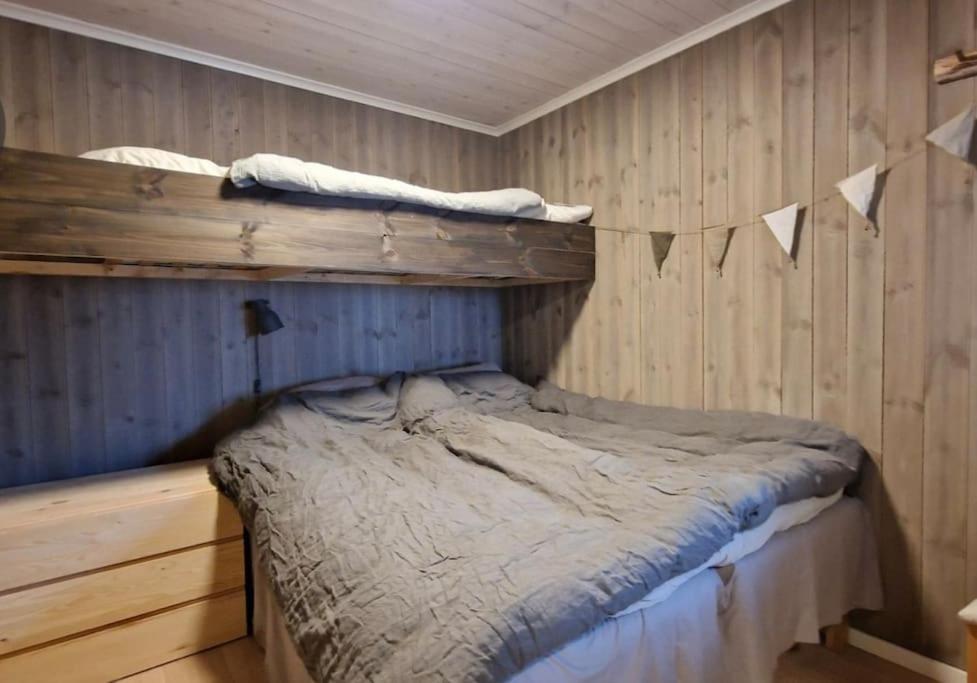uma cama num quarto com paredes de madeira em Hovden Appartment Hovdenut em Hovden