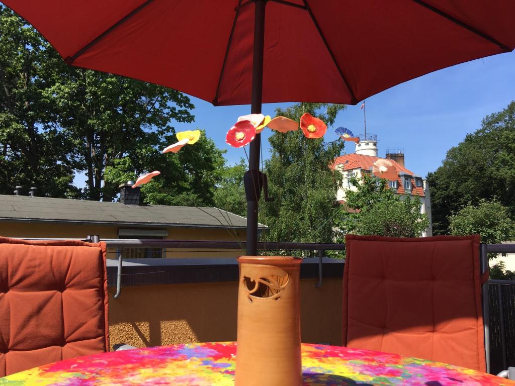 een tafel met een rode parasol op een patio bij Casa del Mar Koserow - 42m bis zum Strand in Ostseebad Koserow