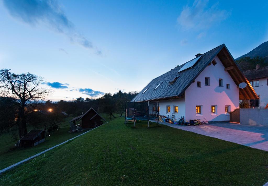 a white house with a black roof on a grass field at Holiday Home Planina in Tržič