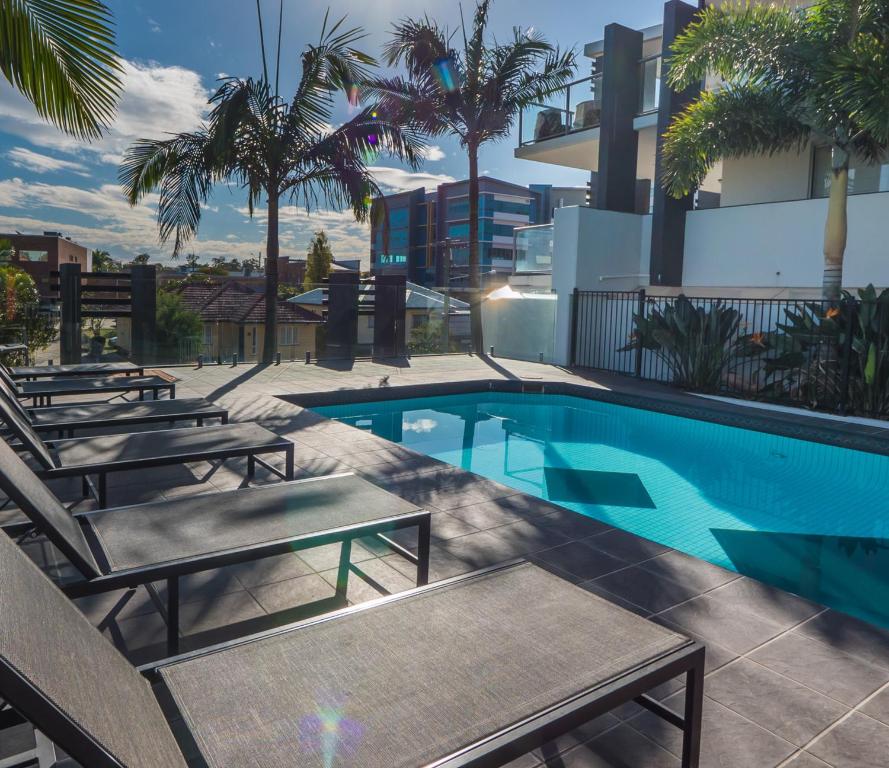 una piscina con sedie a sdraio e un edificio di The Chermside Apartments a Brisbane