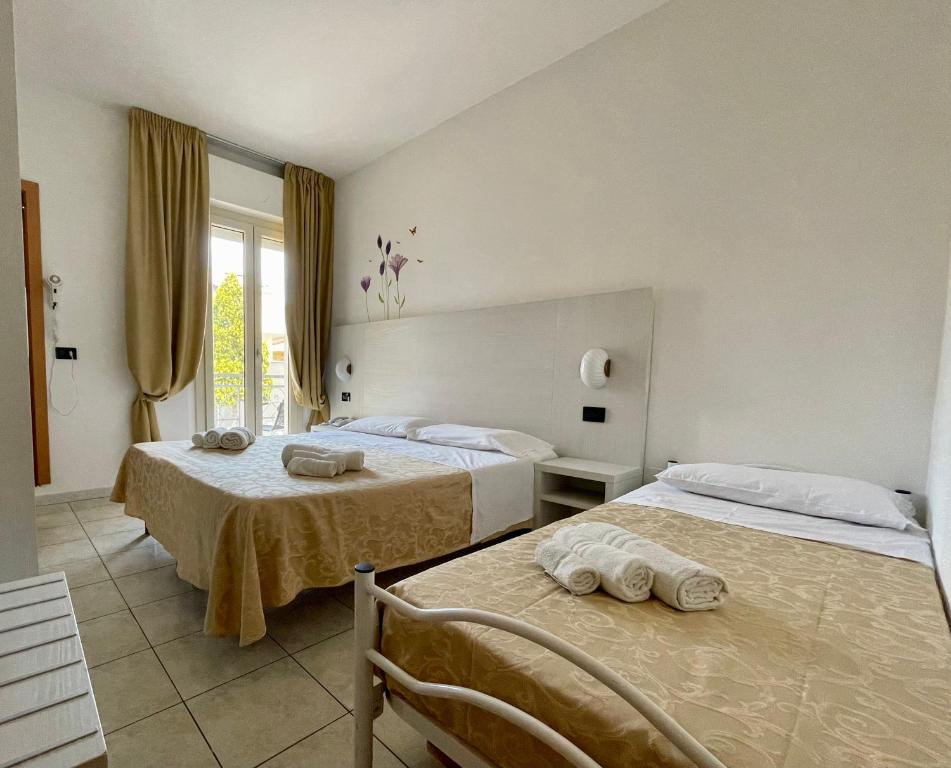 a hotel room with two beds and a window at Dependance Hotel Marina in Riccione
