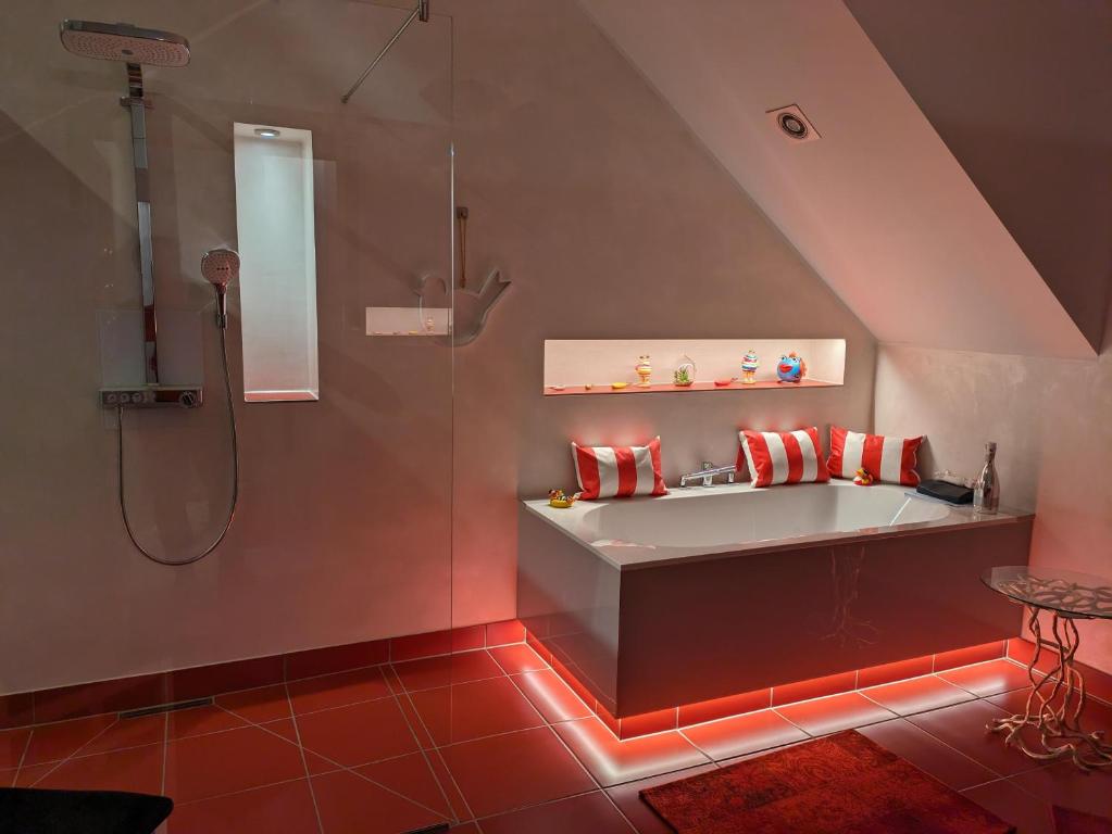 ein Bad mit einer Badewanne und einer Dusche mit roten Lichtern in der Unterkunft Stefans Stadthaus in Saarburg