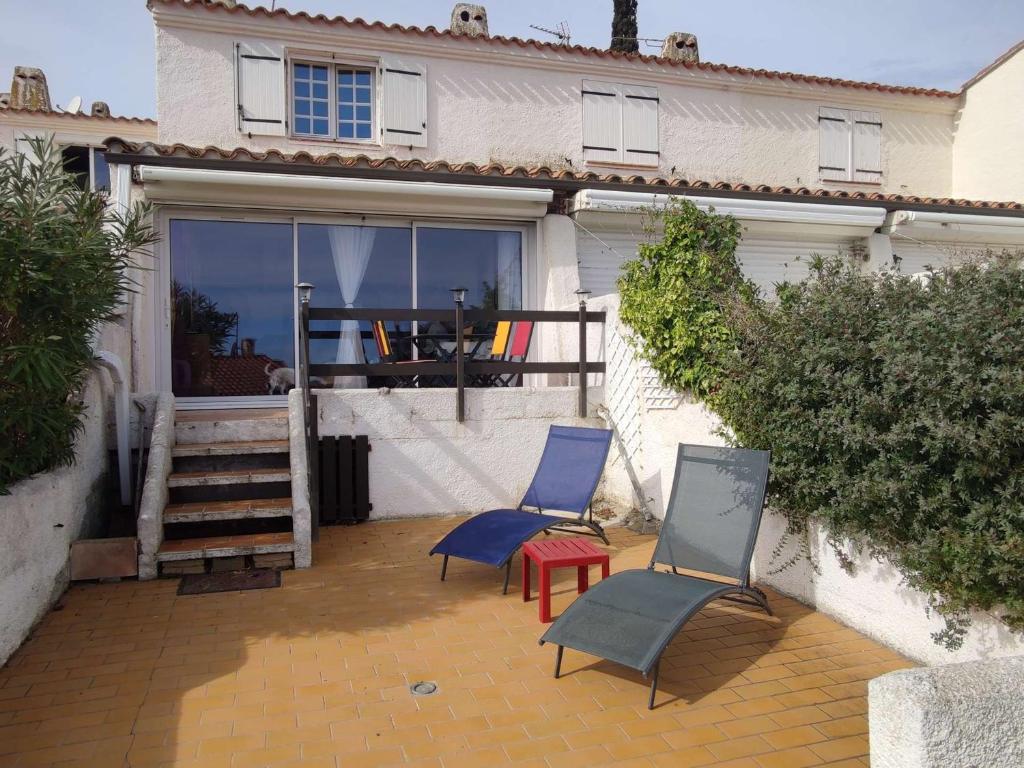 deux chaises et une table devant une maison dans l'établissement Maison 4 pièces, 5 pers, climatisation, terrasse, 450m plage, animaux admis - FR-1-229D-128, à Fleury