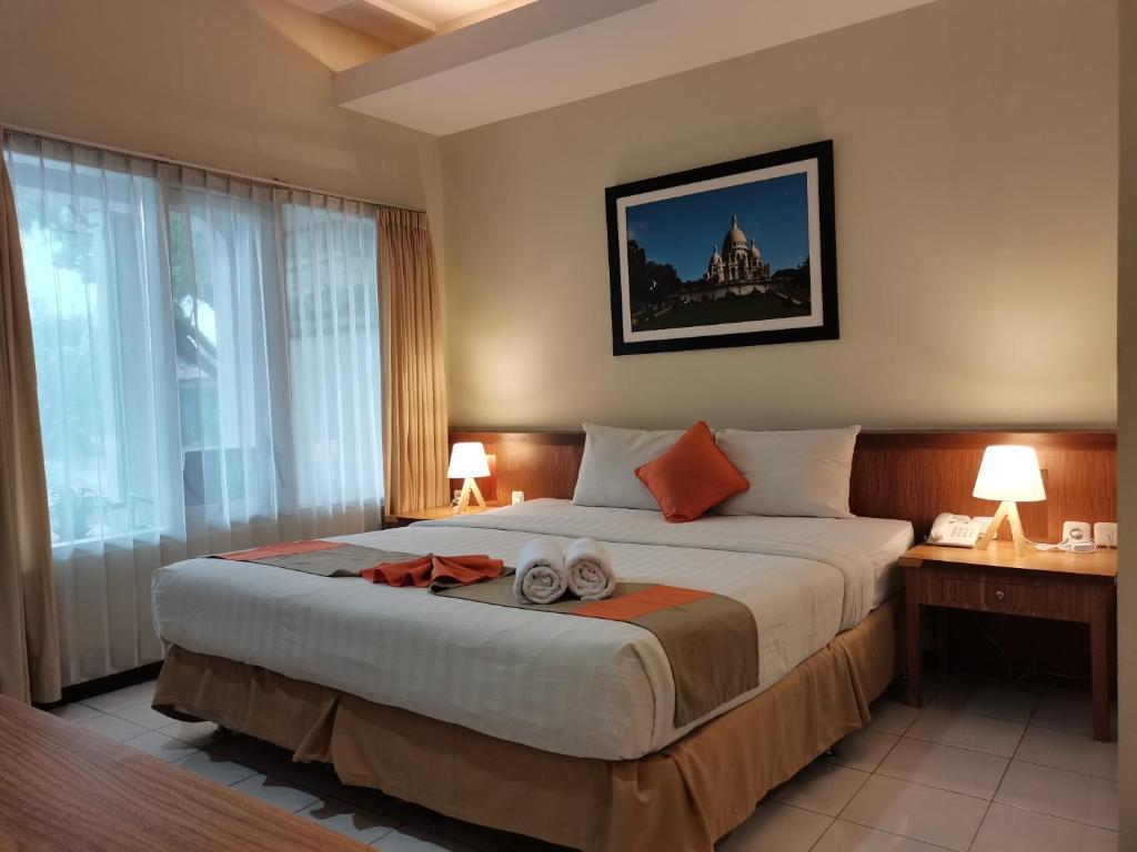 a bedroom with a large bed with two towels on it at Hotel Catur Putra in Magelang