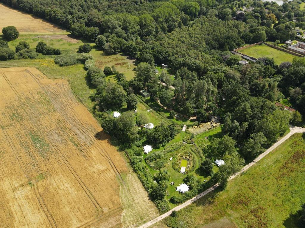 an aerial view of a farm with a field and trees at Moat Island Glamping in Norwich