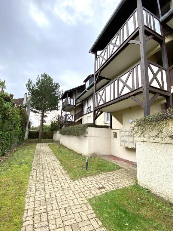 un bâtiment avec une passerelle devant lui dans l'établissement STUDIO AVEC TERRASSE PLEIN SUD - RÉSIDENCE LE FENIL AVENUE DE VERDUN A CABOURG, à Cabourg